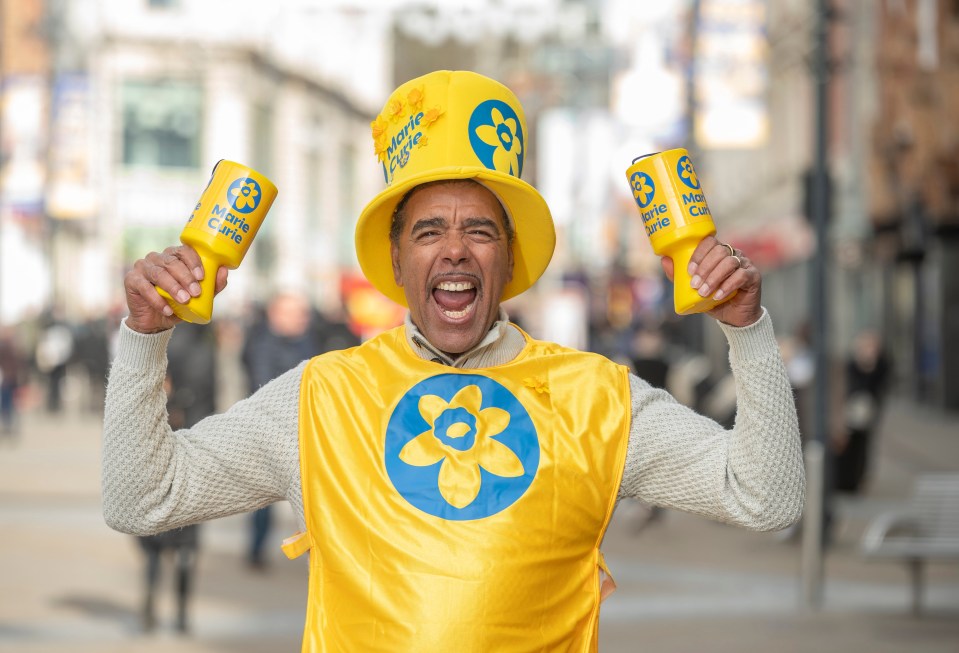 Chris Kamara, a football broadcaster and Marie Curie ambassador, holding donation buckets.