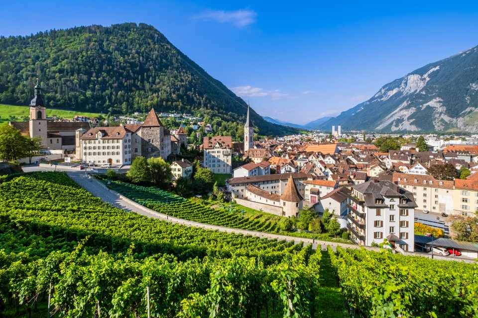 Panorama of Chur, Switzerland's old town, nestled in a valley with vineyards and mountains.