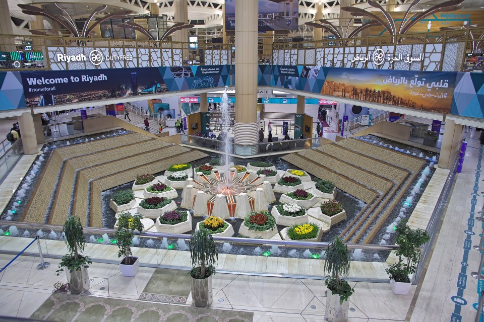 Interior view of King Khalid International Airport in Riyadh, Saudi Arabia, featuring a central fountain surrounded by plants.