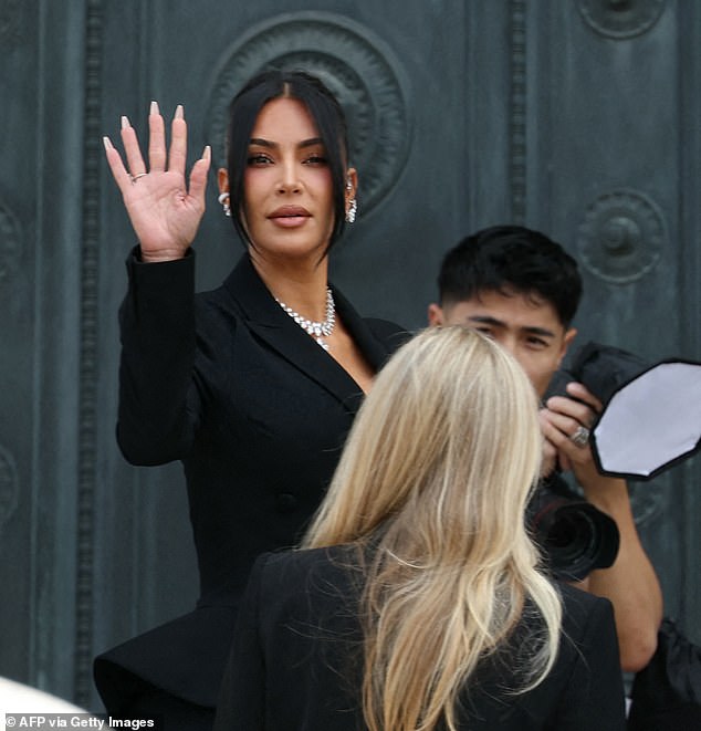 Kardashian - who was dressed in a black trouser suit and sunglasses - waved at onlookers