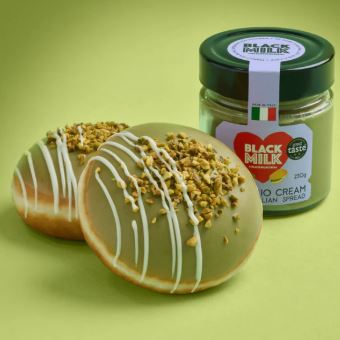 Two pistachio-flavored Krispy Kreme doughnuts with a jar of pistachio cream.