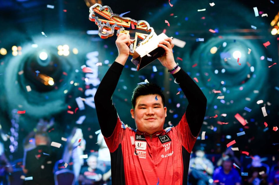 A man holding up a trophy amidst confetti.