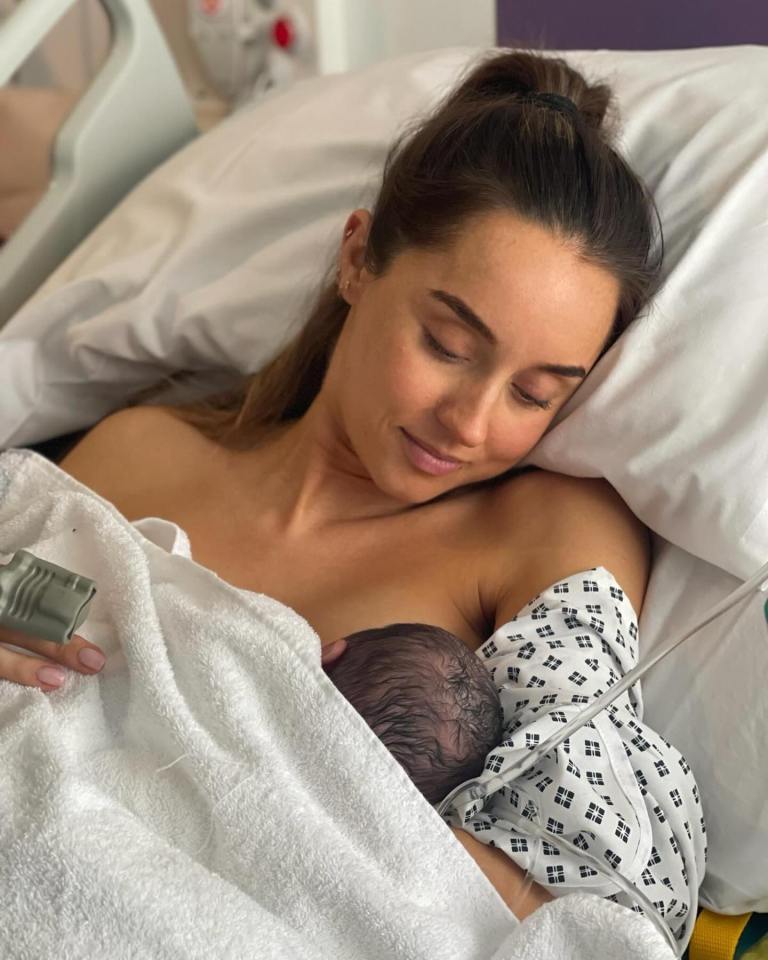 Mother breastfeeding newborn baby in hospital bed.