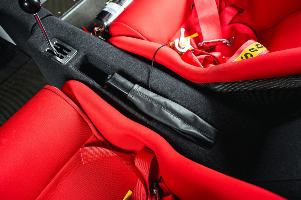 Close-up of a 1989 Ferrari F40's interior, showing the gear stick, seats, and seatbelts.