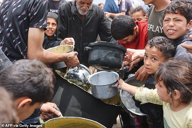 Palestinian children shove to get a ration of hot food from a charity kitchen set up at the Islamic University campus in Gaza City
