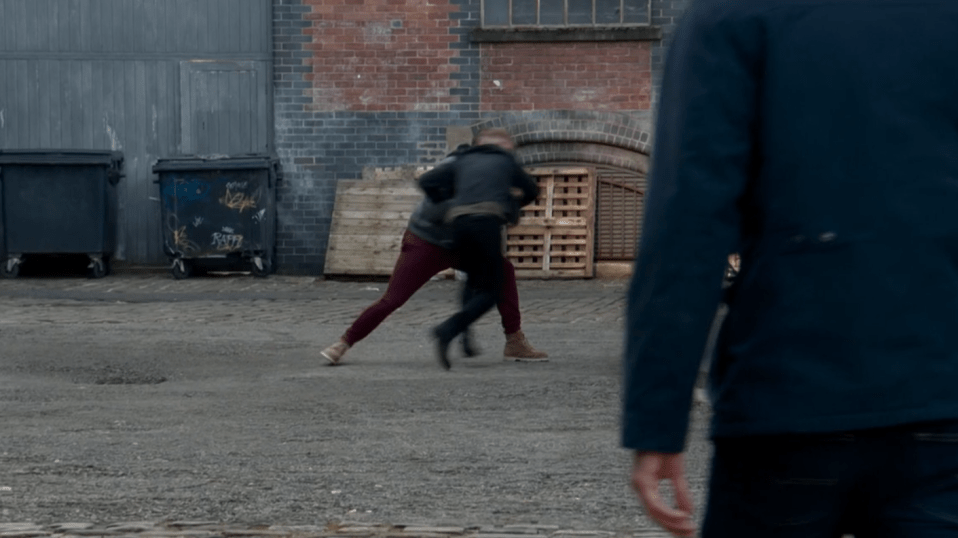 Two people fighting in an alleyway.