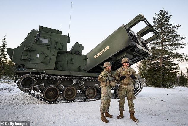 Members of multinational artillery teams stand with an MLRS M270 A2 mobile rocket system during the NATO Exercise Lightning Strike in Finland