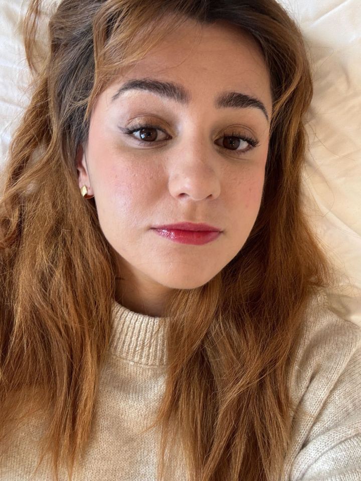 Close-up selfie of a woman with long brown hair and makeup.