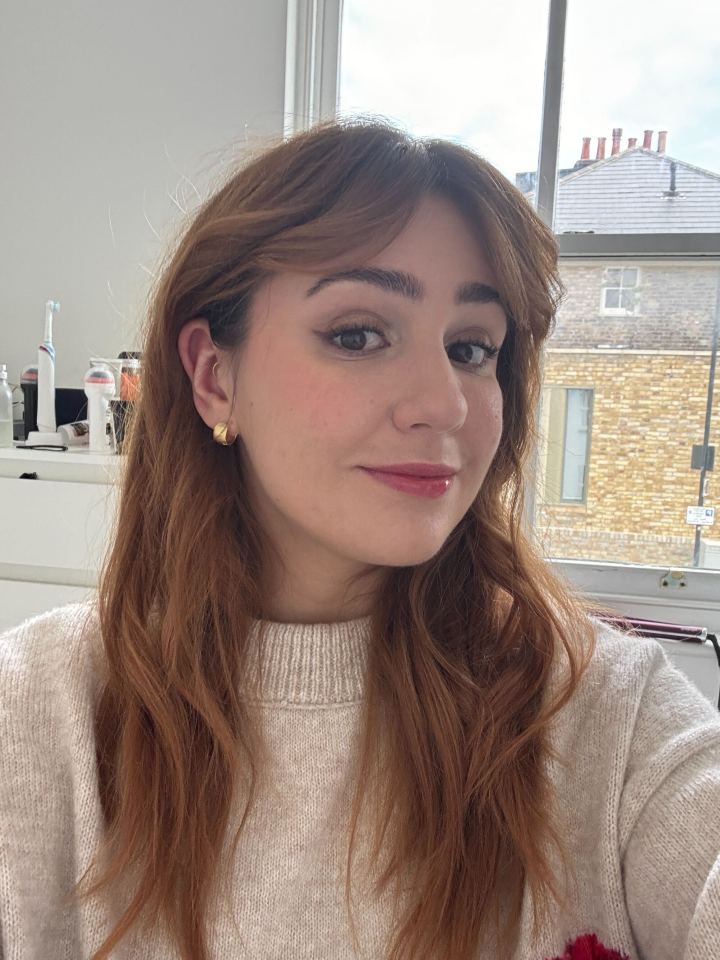 Woman with long brown hair wearing a beige sweater.