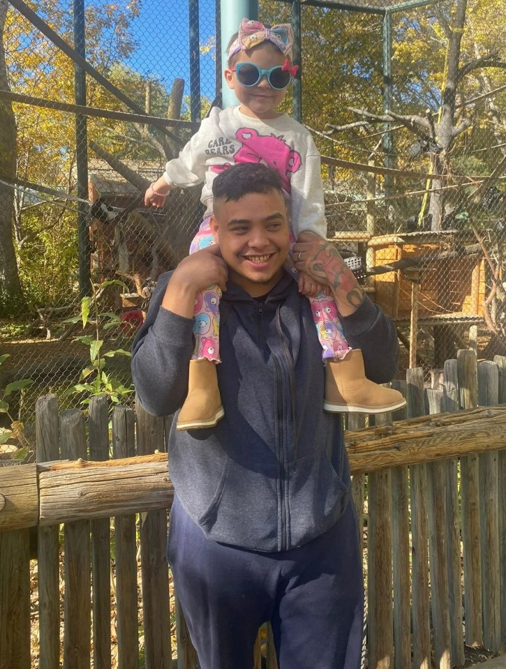 A man carrying a toddler on his shoulders at a zoo.