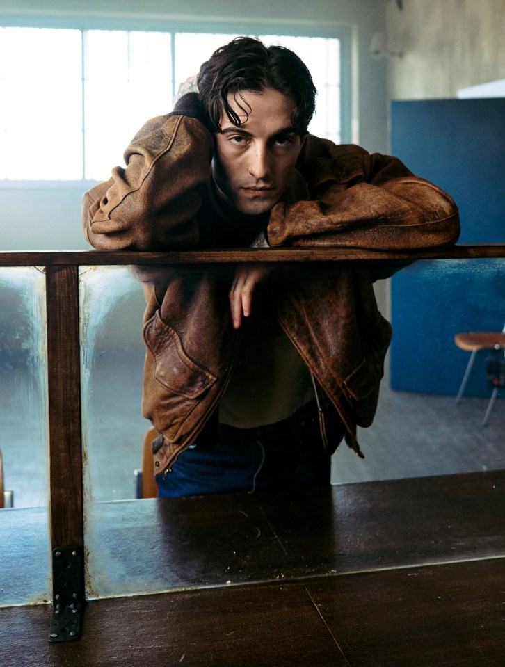 Portrait of Damiano David leaning on a counter.