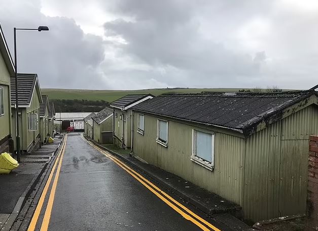 Row of green buildings at Penally Camp in Wales, used to house asylum seekers.