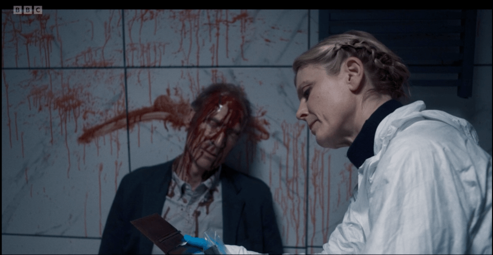 A forensic investigator examines a bloody crime scene.