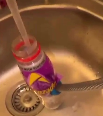 A plastic bottle and a hose in a sink, demonstrating how to ensure free-flowing water.