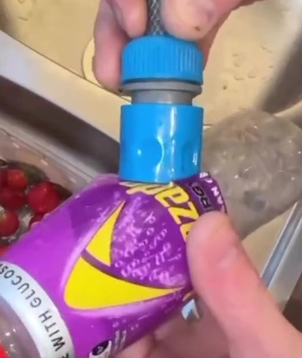 A person inserting a hose pipe into a bottle.