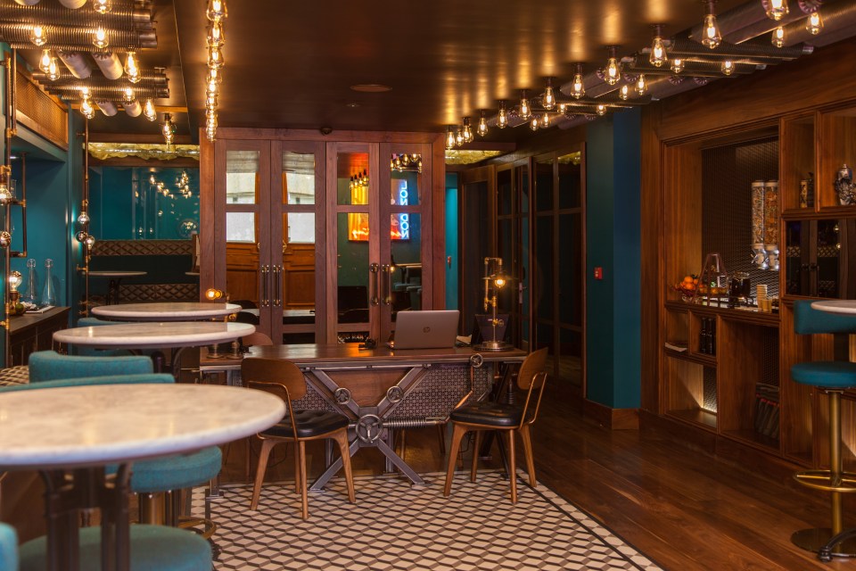 Hotel lobby with teal walls, marble-top tables, and steampunk-style lighting.