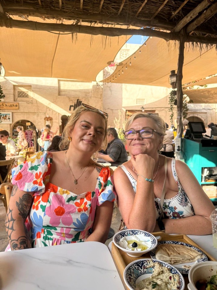 Two women sitting at a table outdoors, sharing a meal.
