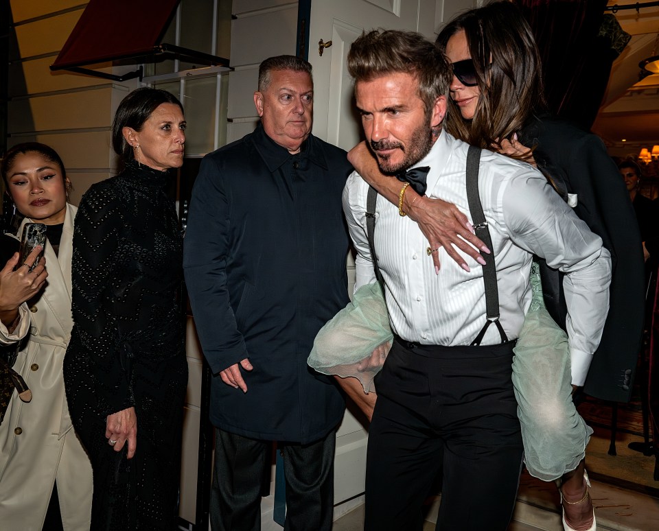 David Beckham carrying Victoria Beckham on his back.