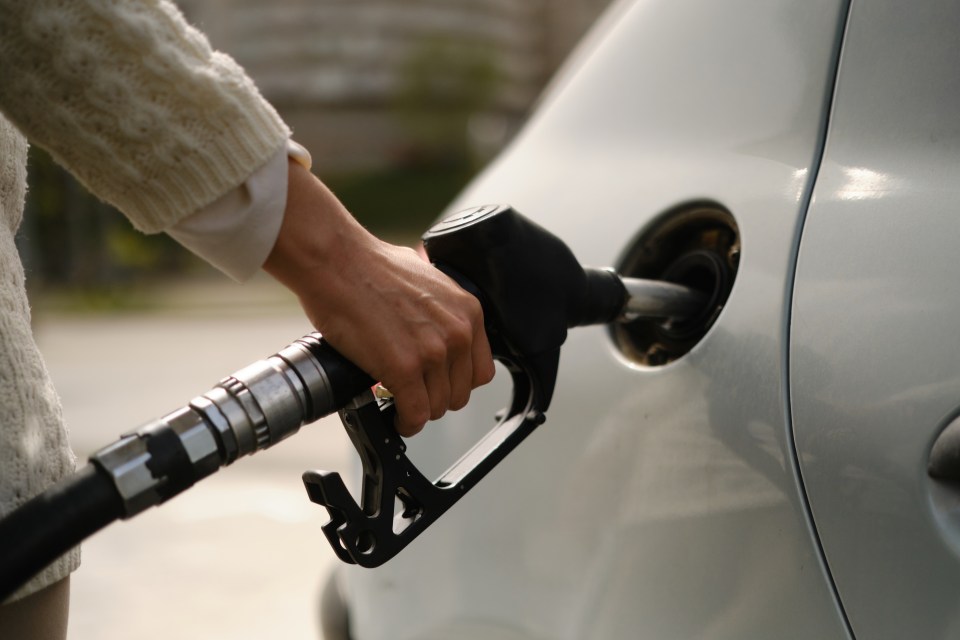 Woman pumping gas into a car.