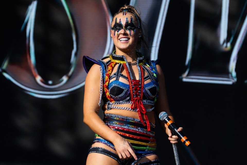 A performer in a colorful, sequined costume holds a microphone at Mighty Hoopla 2024.
