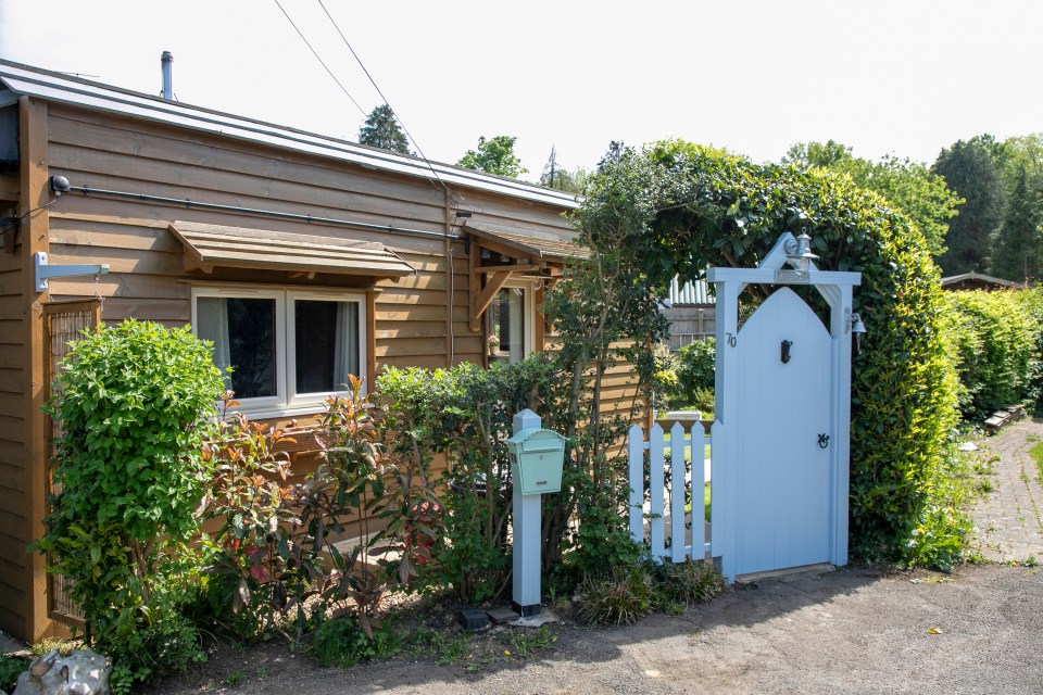 Small wooden house with a light blue gate and mailbox.