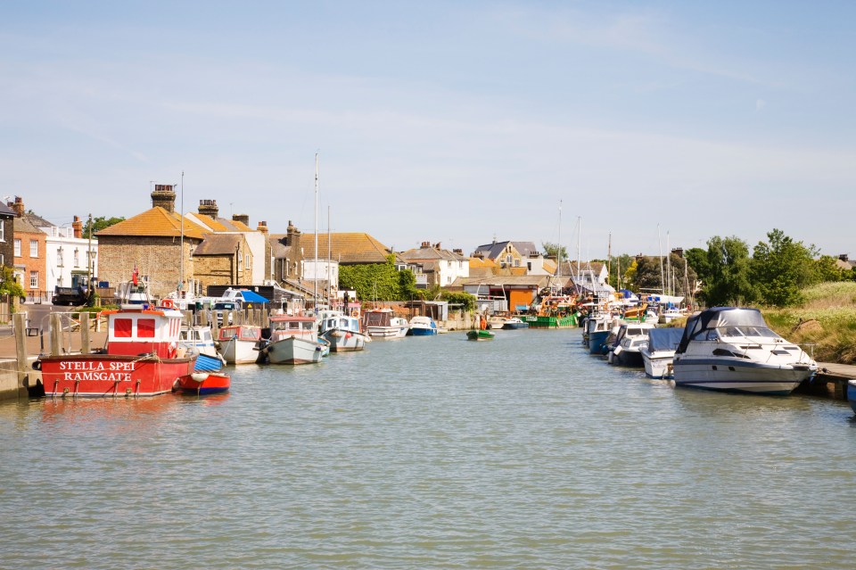 Queenborough harbor in Kent, England, with boats moored along the waterfront.
