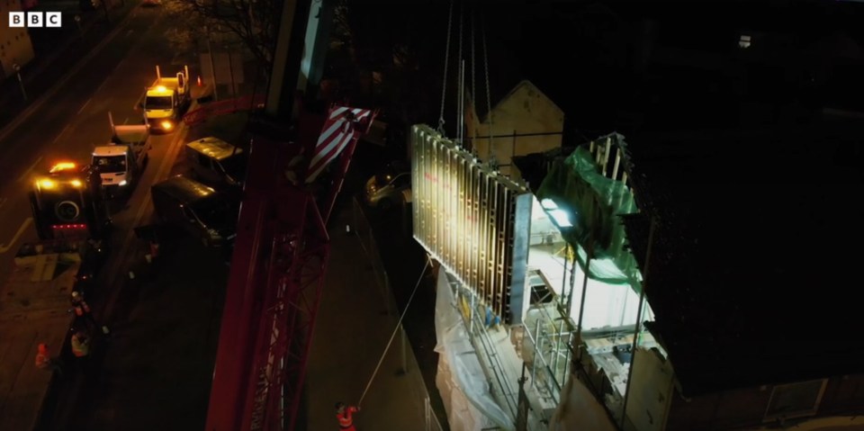 Nighttime removal of a seagull mural from a building using a crane.