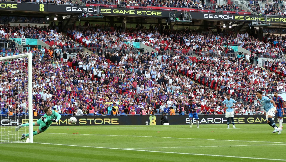 Dean Henderson saving a penalty kick from Omar Marmoush during a soccer game.