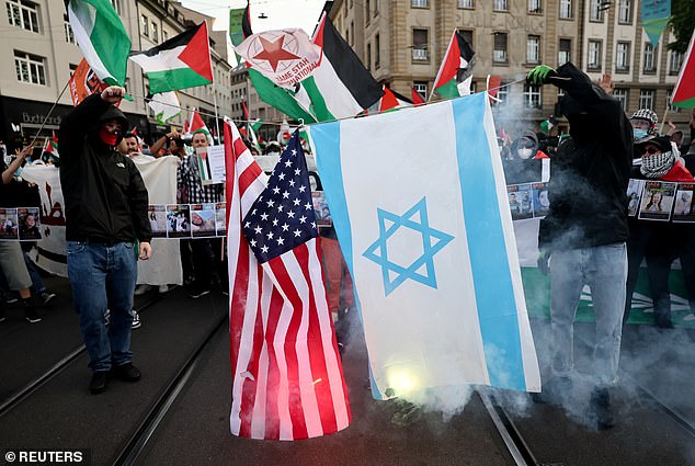 Pro-Palestinian demonstrators set alight an Israel and a US flag at the protests in Basel this evening