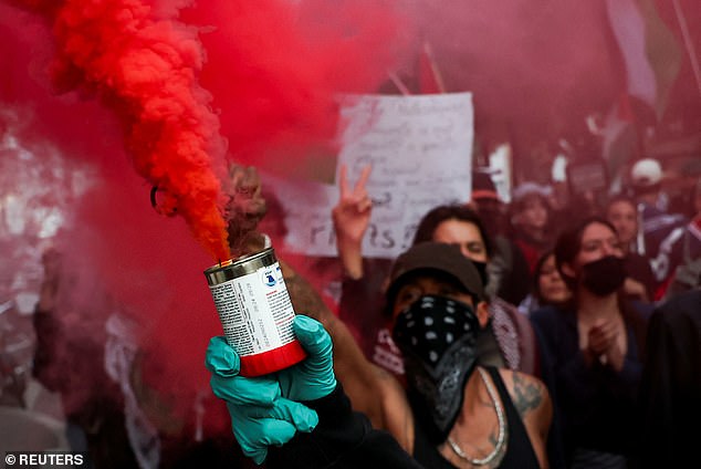 A red smoke flare is released into the air by a pro-Palestine marcher as they demonstrate against Israel's participation in the Eurovision final