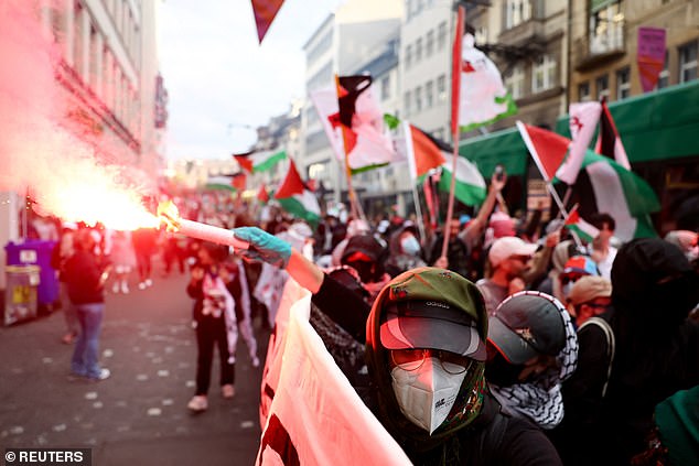 Pro-Palestinian demonstrator releases a flare on the street of the Swiss city ahead of the Eurovision this evening