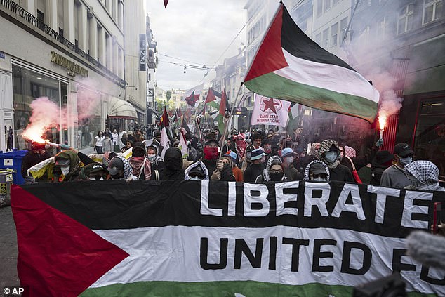 A sign which reads 'Liberate Eurovision, United for Palestine' as protestors release flares on the streets