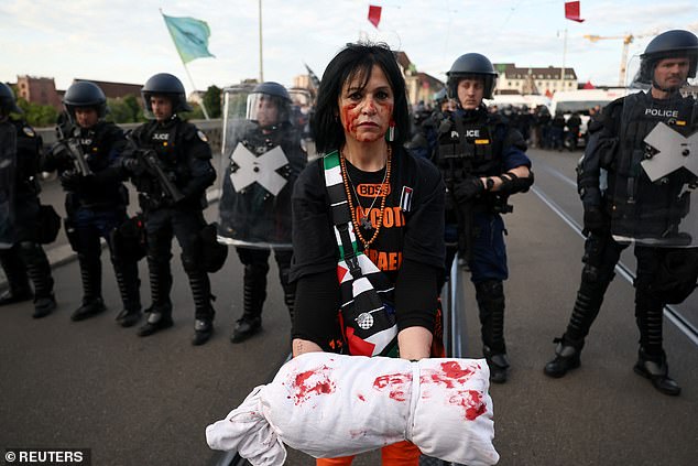 A pro-Palestine marcher holds a prop symbolising a body bag smeared with blood in front of armed police