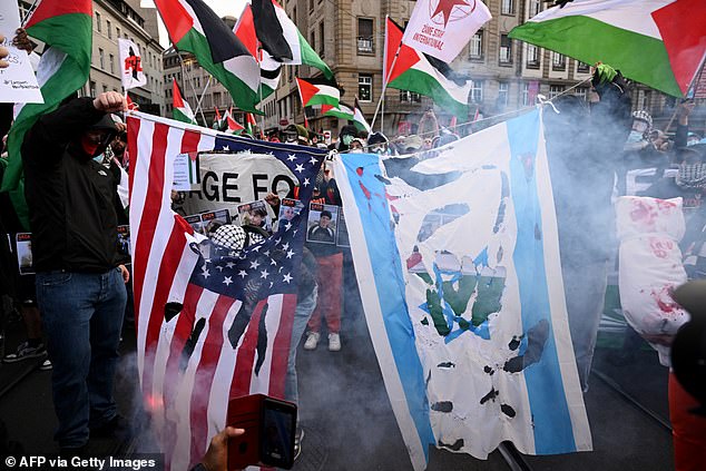 The Israeli and US flag in tatters, smoking after being set alight by protesters in Basil