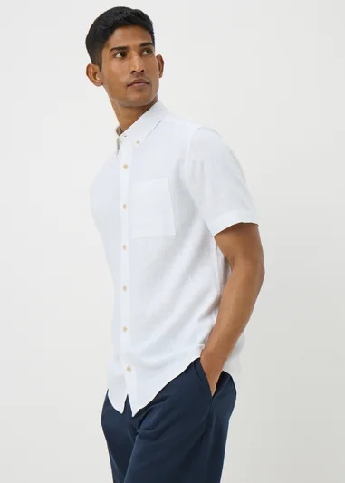 Man wearing a white short-sleeve button-down shirt and dark blue pants.