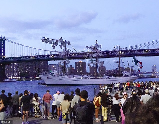 People look at the Cuauhtémoc, a Mexican Navy training boat, as it sits in the East River after the ship hit the Brooklyn Bridge, in New York on Saturday evening