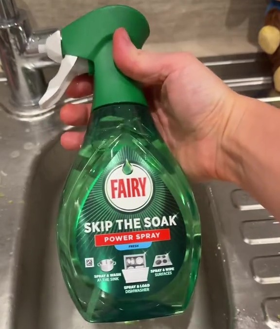 Hand holding Fairy Skip the Soak Power Spray bottle over a sink.