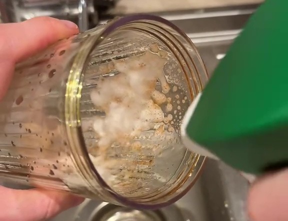 Cleaning a stained blender with a spray cleaner.