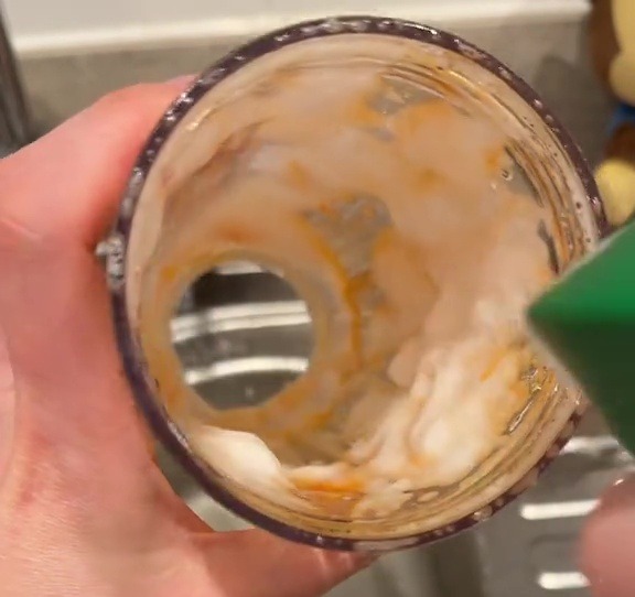 A stained blender cup being cleaned with a cleaning spray.