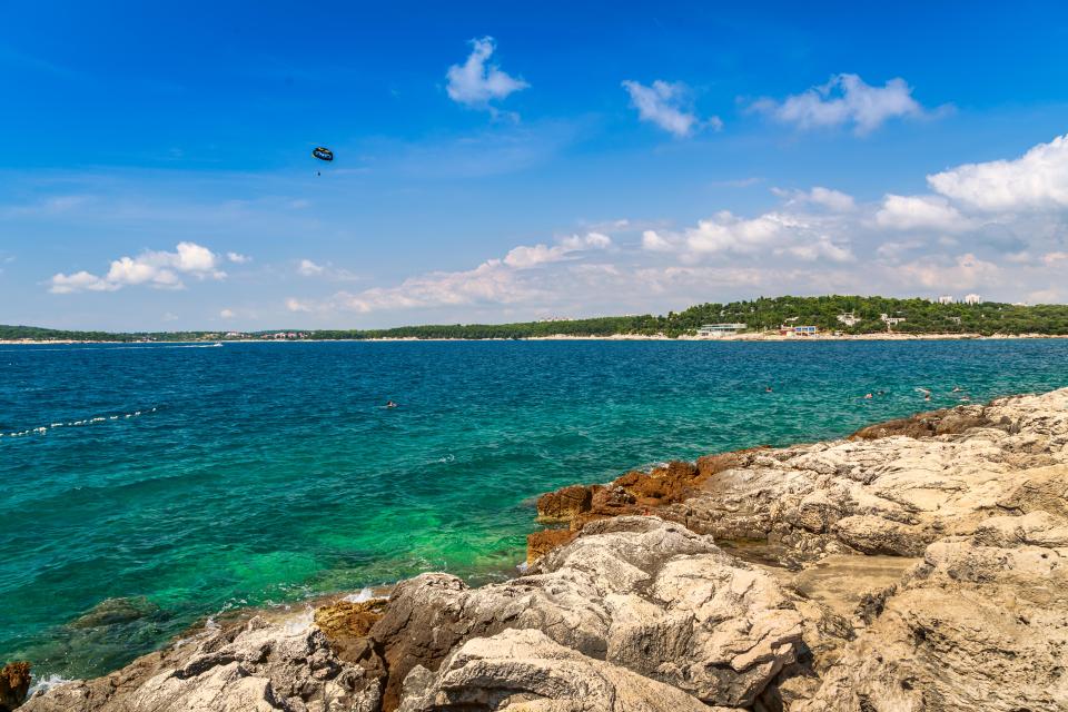 Parasailing over a rocky beach in Pula, Croatia.