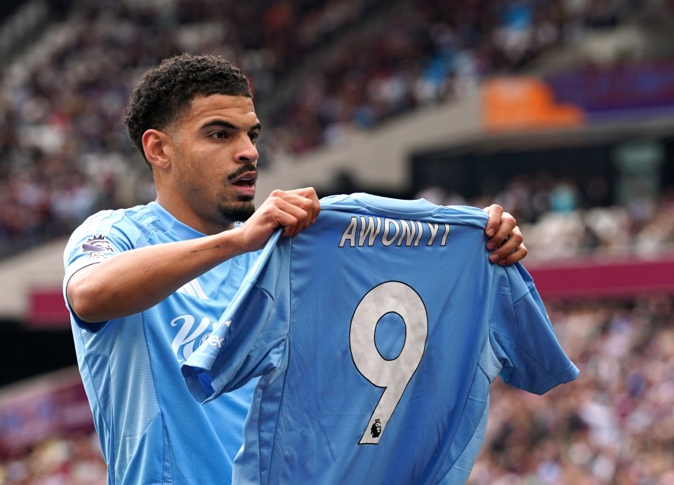 Nottingham Forest players celebrating a goal while holding up a jersey with "Awoniyi 9" on it.