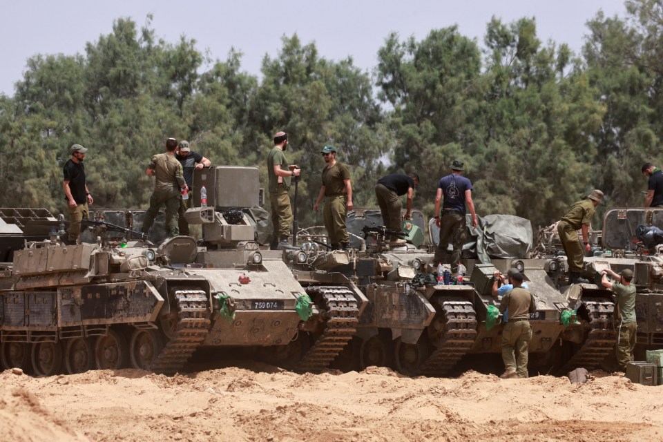 Israeli soldiers working on armored vehicles near the Gaza Strip border.