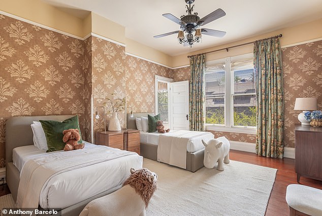 Cozy guest bedroom with two beds, a modern ceiling fan, and wallpaper accent walls