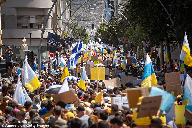 Thousands of people wave Canary Islands flags as they protest against tourism on the islands