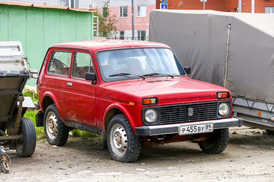 Red Lada Niva 4x4 parked on a city street.