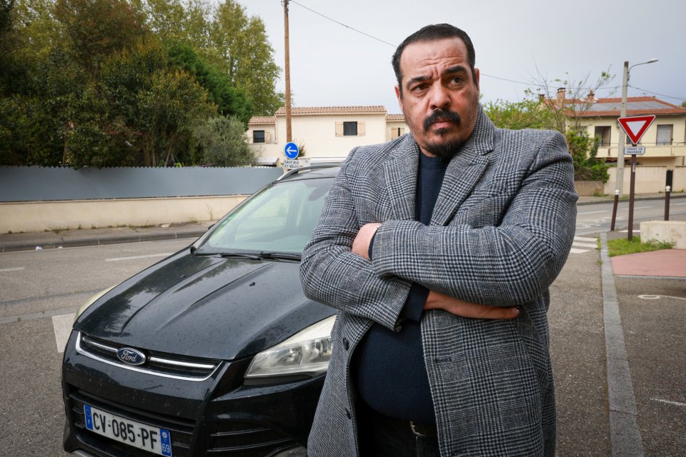 Private hire driver Nasim Mimun standing by his car, accusing members of the British government of non-payment.