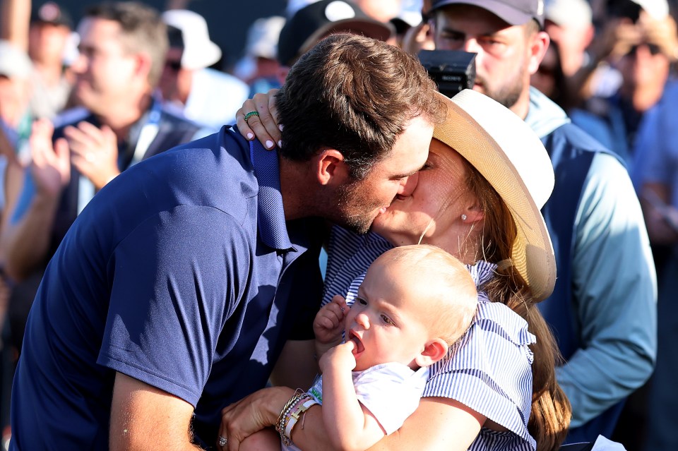 Scottie Scheffler kisses his wife while holding their baby.