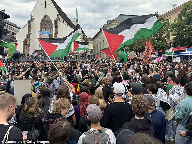 The crowds of Palestinian supporters (pictured) held signs which read 'boycott Israel apartheid' and 'no stage for genocide', as they waved flags and released flares into the sky
