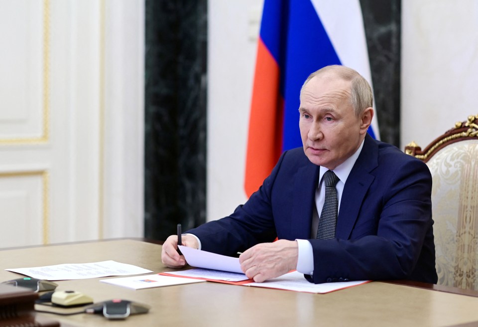 Vladimir Putin reviewing documents at a meeting.