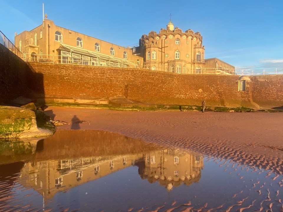 Reflection of a building in a tidal pool on a sandy beach.